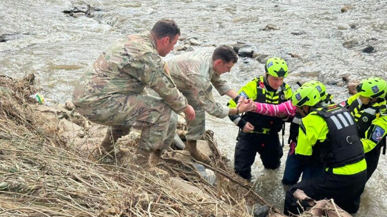 Photo of rescue workers helping pull someone from a flooded river.